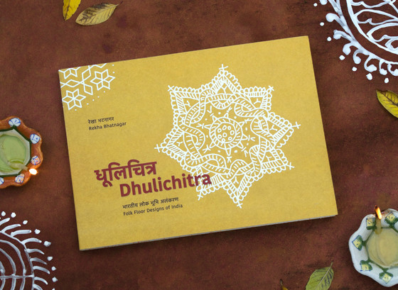 Dhulichitra Book Photograph of Dhulichitra book with floor decorations, earthen lamps and fallen leaves around